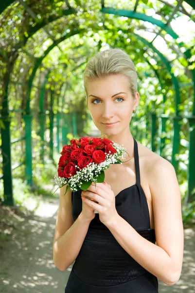 Belle fille blonde tenant bouquet de roses rouges — Photo