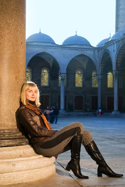 Beautiful blond girl sitting near the column — Stock Photo, Image