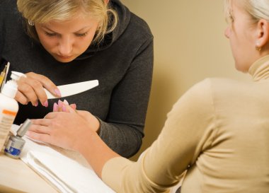 Manicurist polishing client's nails clipart