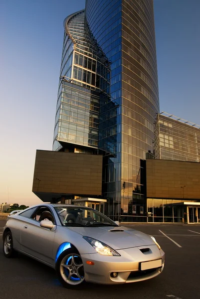 Спортивный автомобиль с офисным зданием и чистым голубым небом позади него — стоковое фото