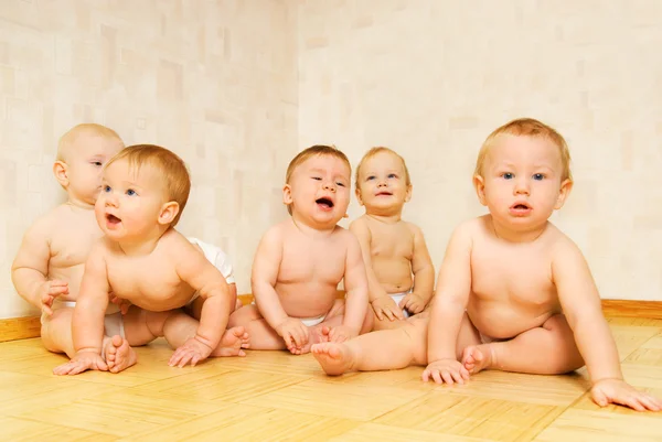 Grupo de crianças adoráveis sentadas em um chão — Fotografia de Stock