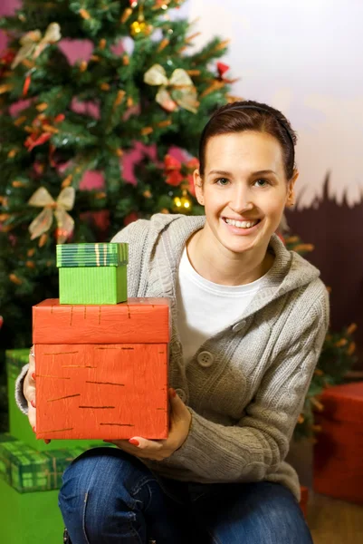 Teenager girl with gift boxes, Christmas three behind her — Stock Photo, Image