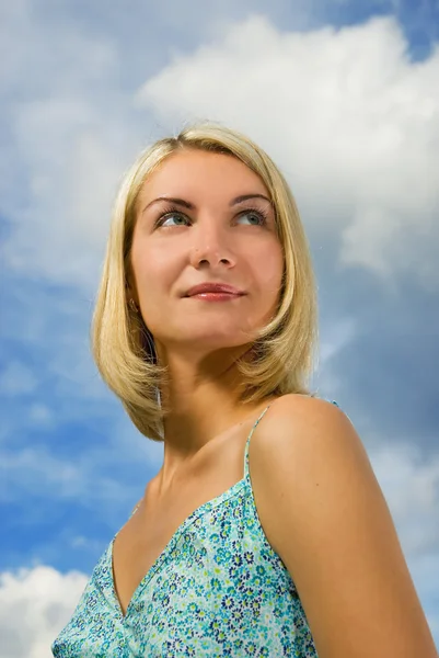 Prachtige blond meisje en blauwe bewolkte hemel achter haar — Stockfoto