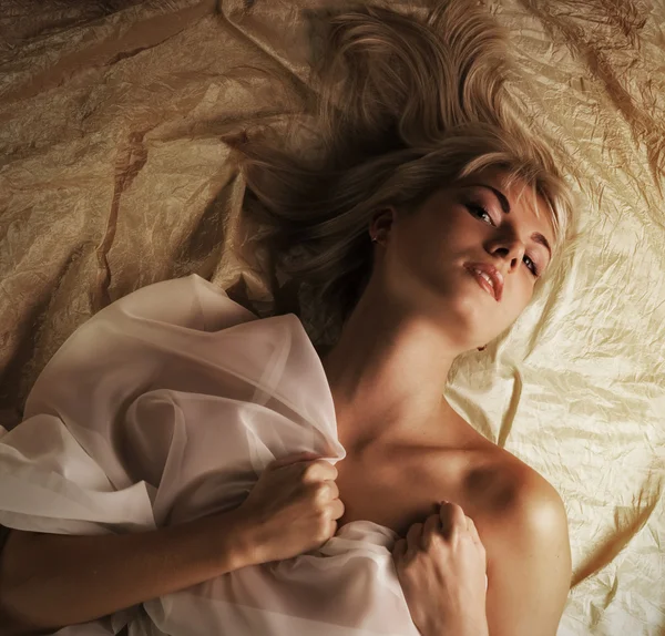 Retrato de uma linda linda menina loira deitada em uma cama — Fotografia de Stock