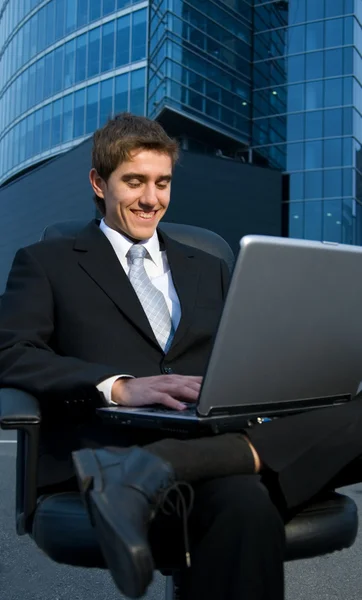 Bonito empresário confiante trabalhando em seu laptop na frente de — Fotografia de Stock