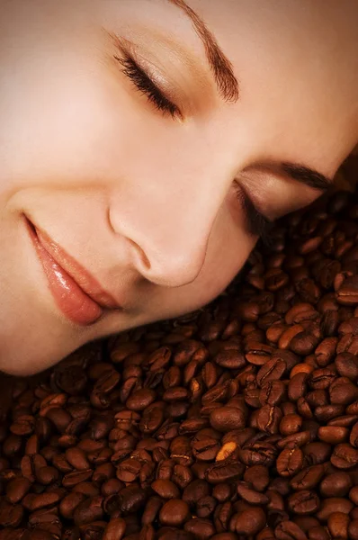 Mooi meisje gezicht over koffie bonen — Stockfoto