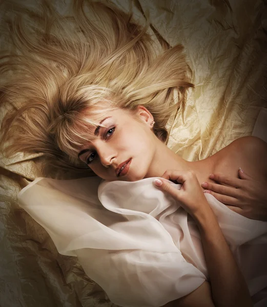 Όμορφη ξανθιά κοπέλα που βρίσκεται σε ένα κρεβάτι — Φωτογραφία Αρχείου