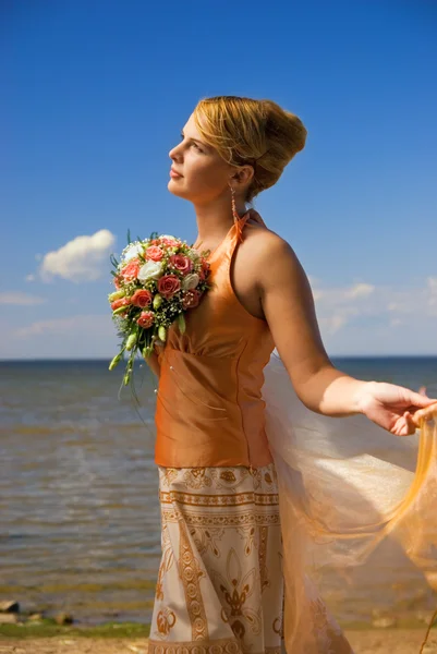 Bella signora rossa con un mazzo di fiori vicino al mare — Foto Stock