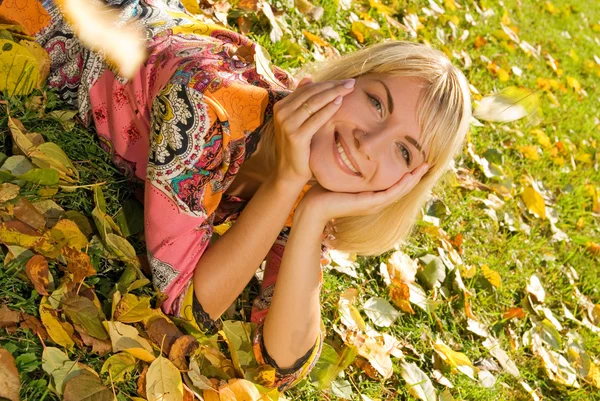 金发碧眼性格开朗的女孩躺在秋天的树叶 — 图库照片
