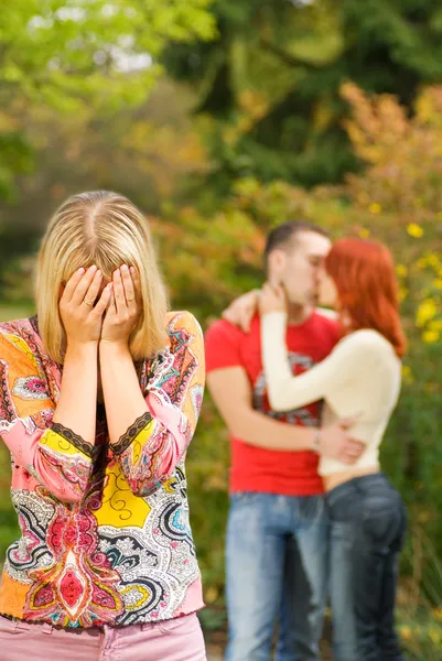 Gråtande flicka och kyssande par på en bakgrund — Stockfoto