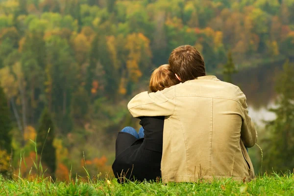 Doce casal sentado em uma colina e olhando para a landsca outono — Fotografia de Stock