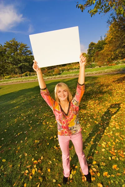 白い板を保持している秋の背景に美しい女の子 — ストック写真