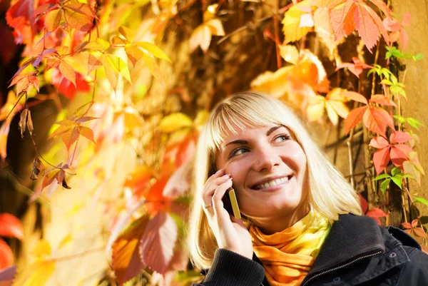 幸せな女の子彼女の背後に秋の背景携帯電話で話す — ストック写真