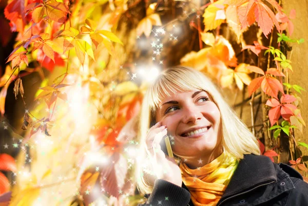 Happy girl talks to on the phone, abstract autumn background beh — Stock Photo, Image
