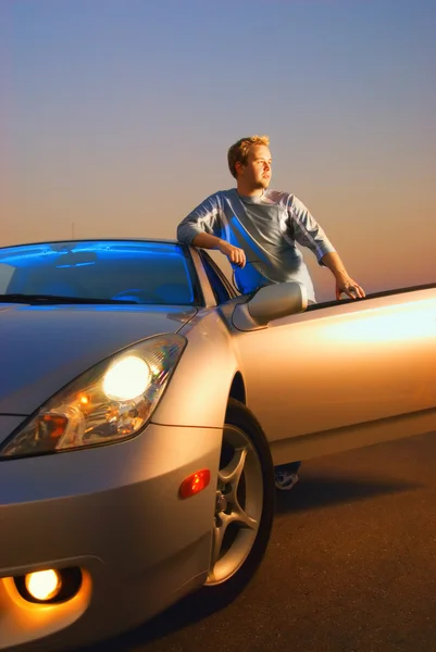 日没時に近代的なスポーツ車の近くのハンサムな男 — ストック写真