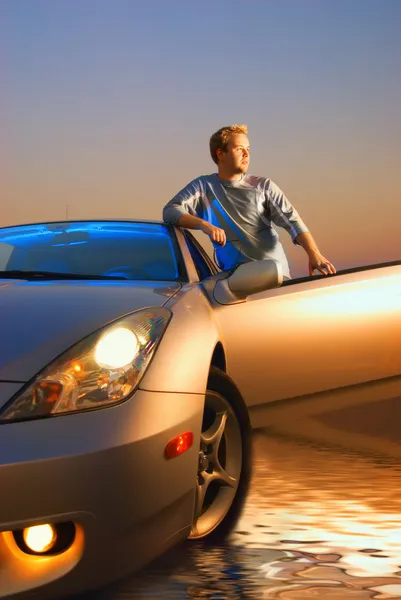Jóképű srác közelében a modern sport autó a napnyugta időpontja — Stock Fotó