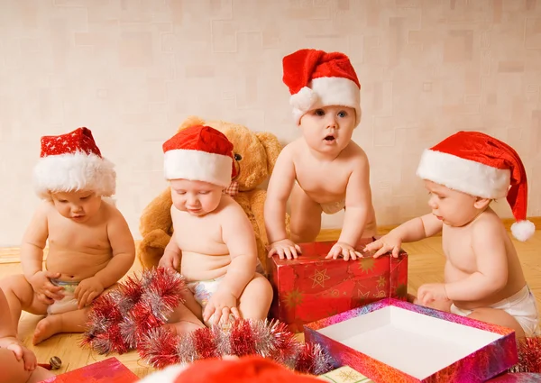 Группа очаровательных малышей в рождественских шляпах упаковывает подарки Стоковое Фото