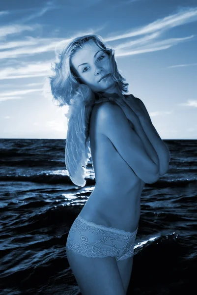 Девочка-ангел в море на закате (окрашена в синий цвет) ) — стоковое фото