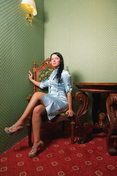 Morena sentada em uma cadeira em um armário de luxo — Fotografia de Stock