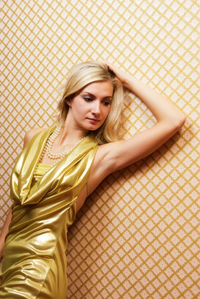 Schöne blonde Mädchen in goldenem Kleid auf abstraktem Hintergrund — Stockfoto