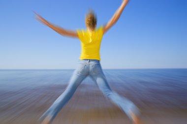 Girl jumping on the beach (blur filter applied to give sence of clipart