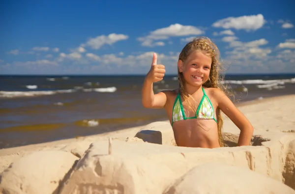 Menina sentada em um carro feito de areia e mostrando a mão com — Fotografia de Stock