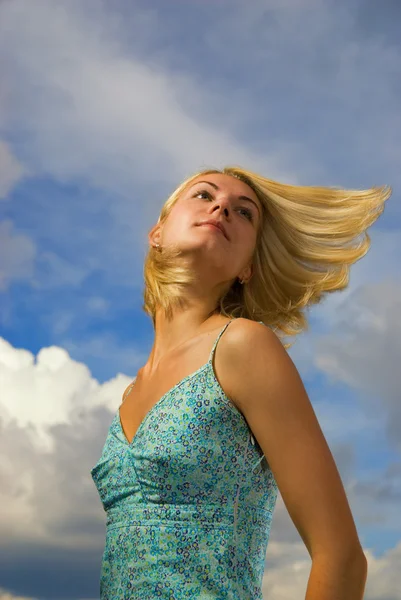 Menina loira bonita e céu nublado azul atrás dela — Fotografia de Stock