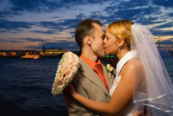 Просто женатая пара целуется у реки на закате — стоковое фото