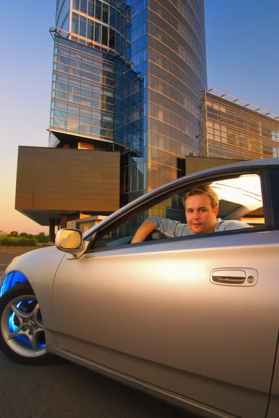 Stilig kille sitter en sportbil vid solnedgång — Stockfoto