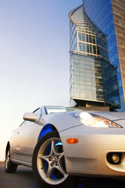 Carro esporte com prédio de escritórios e céu azul claro atrás dele — Fotografia de Stock