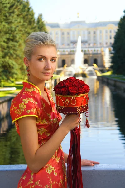 Beatutiful blonde Mädchen mit einem Strauß roter Rosen — Stockfoto