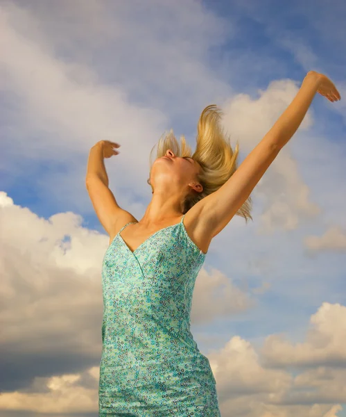 Prachtige blond meisje bewolkte achtergrond achter haar — Stockfoto
