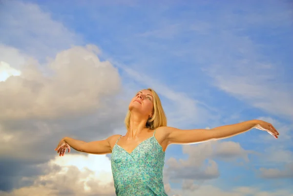 Hermosa chica rubia con los brazos abiertos sobre el cielo nublado azul — Foto de Stock