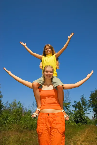 The girl with arms wide open, clear blue sky behind them — Stock Photo, Image