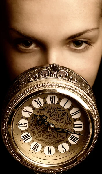 Sepia picture of a girl's face with a clock (focus on clock) — Stock Photo, Image