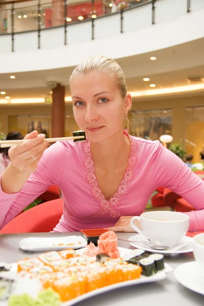 Κορίτσι τρώει σούσι σε μια αίθουσα εκδηλώσεων-εστιατόριο — Φωτογραφία Αρχείου