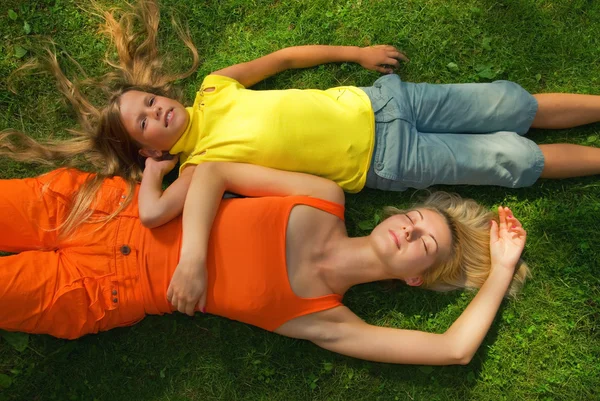 Две девушки лежат на зеленой траве — стоковое фото