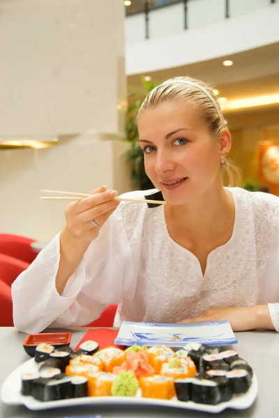 Beautiful girl eats sushi in a restaurant — Stock Photo, Image