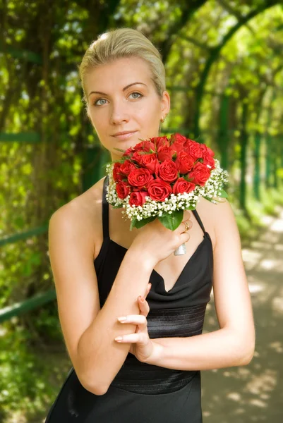 Bella ragazza bionda in abito da sera che tiene bouquet di ros rosso — Foto Stock