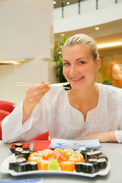 Çekici sarışın kız suşi bir restoranda yiyor. — Stok fotoğraf