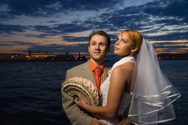 stock image Bride and groom standing together near the river at the sunset t