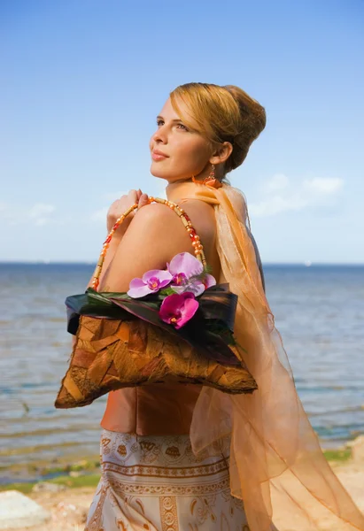 stock image Happy redhead girl on the beach holding floral handbag