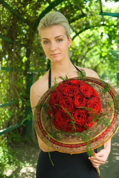 Blondes Mädchen mit einem Strauß roter Rosen — Stockfoto