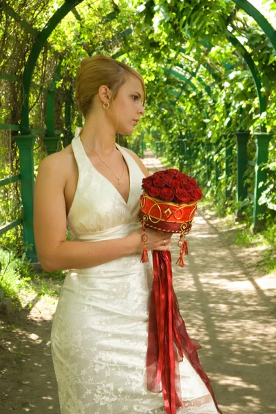 Girl with a bouquet of roses in green alley — Stock Photo, Image