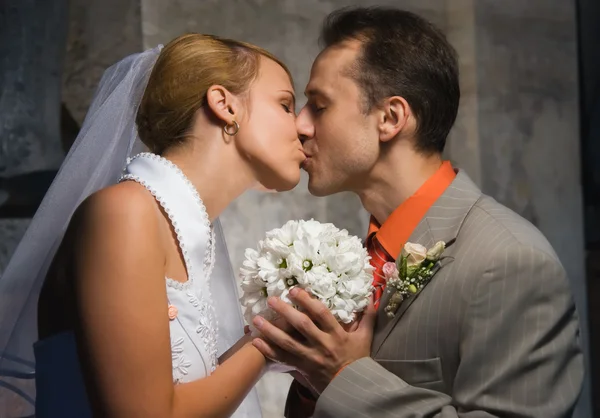 Eheleute küssen sich und halten einen runden Strauß weißer Blumen in der Hand — Stockfoto