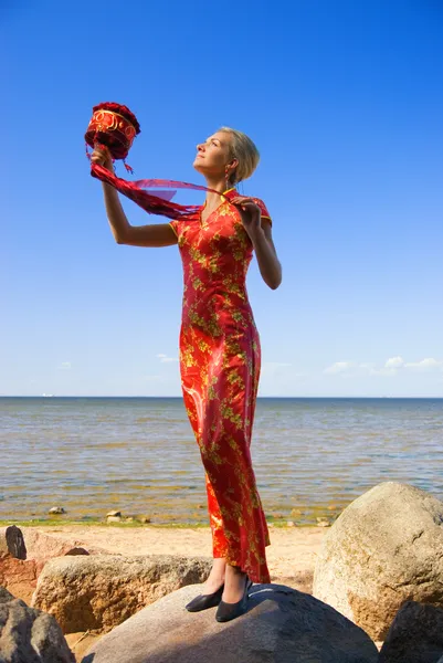 Bella ragazza bionda con un mazzo di rose rosse in piedi sul — Foto Stock