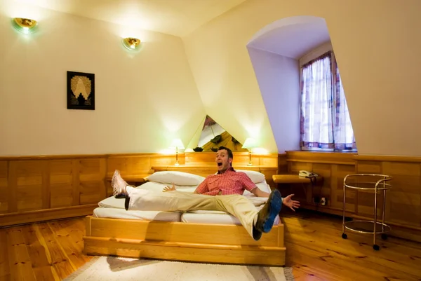 Happy tourist jumps on a bed in hotel room — Stock Photo, Image