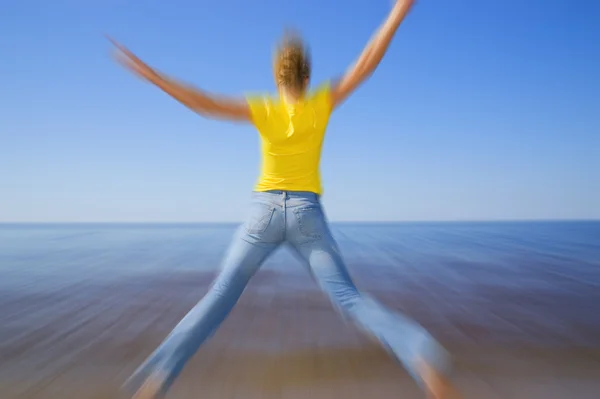Девушка, прыгающая на пляже (фильтр размытости применяется, чтобы дать ощущение — стоковое фото