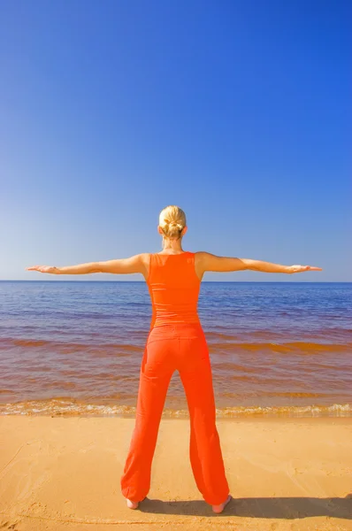 Blond meisje mediteren op het strand — Stockfoto