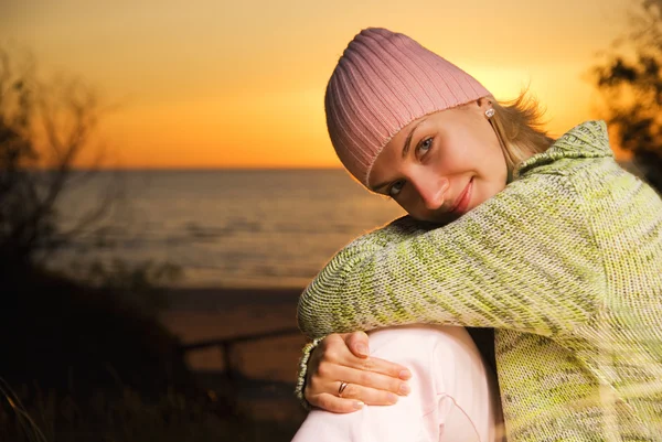 Giovane ragazza seduta sulla spiaggia al tramonto — Foto Stock